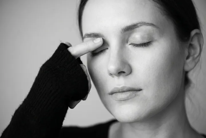 Woman gently touching her closed eyelid